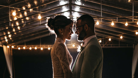 Smiling married couple embracing under warm white patio lights