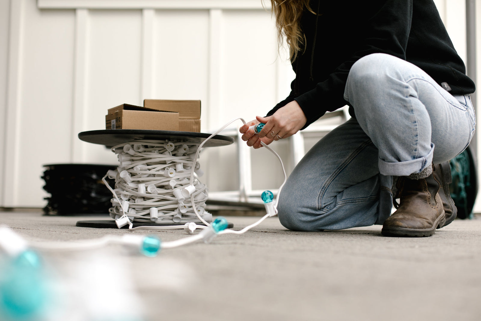 Person in blue jeans bulbing teal G30 bulbs into white wire E17 Spool